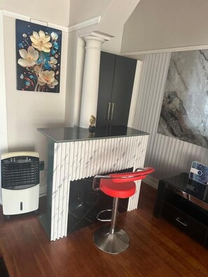 A kitchen with a bar area, a white column, a black cabinet, and a red bar stool. - Comrades villa guest house  (Pietermaritzburg)