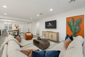A modern living room with a sofa, a coffee table, and a TV mounted on the wall. - NEW|The Ellington|Pool+Hottub+Game Table|Sleeps 10 (Fountain Hills)