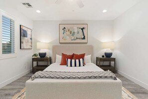 A bedroom with a bed, two bedside tables with lamps, a ceiling fan, and artwork on the walls. - NEW|The Ellington|Pool+Hottub+Game Table|Sleeps 10 (Fountain Hills)