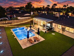 Un jardin avec une piscine, du mobilier d’extérieur et un patio couvert.
