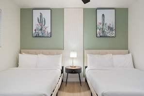 A hotel room with two beds, a nightstand with a lamp, and two framed cactus paintings on the walls. - NEW| Casa Alegre "Happy House"| FREE Heated Pool (Scottsdale)