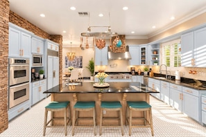 A modern kitchen with a central island, stainless steel appliances, and light blue cabinetry.