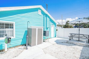 A turquoise building with a small outdoor area, a water fountain, and a picnic table. - Turquoise Mermaid Cottage at White Sands | updated 1 br/1ba steps to beach (Indian Rocks Beach)