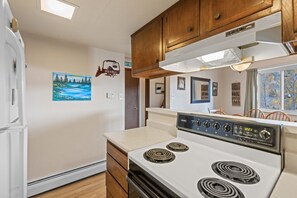 A compact kitchen with a stove, cabinets, and a window. - Lake Dillon and Mountain Views! (Dillon)