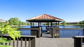 A wooden deck leading to a gazebo with a metal roof overlooking a body of water. - Near Disney at Encantada Resort Cozy Townhouse (Kissimmee)