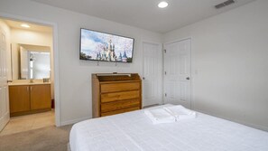 A bedroom with a bed, a dresser, a television on the wall, and a door. - Near Disney at Encantada Resort Cozy Townhouse (Kissimmee)