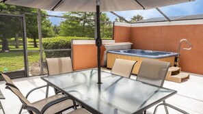A glass-top table with chairs, a hot tub, and a patio umbrella. - Near Disney at Encantada Resort Cozy Townhouse (Kissimmee)