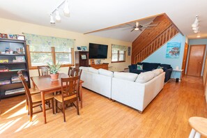 A spacious living area with a dining table, chairs, a sofa, and a staircase leading to an upper level. - Oceanside- Near Ocean, Priv Pool, Close to Shopping-SH110 (Duck)