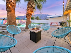 An outdoor patio with a fire pit, lounge chairs, and a pool area. - Gorgeous Mountain Sunset Casita with AC Heated Pool Hot Tub Fire pit EV Charger (Palm Springs)