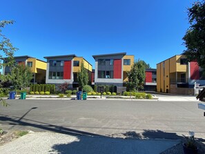Eine Reihe moderner mehrstöckiger Gebäude mit flachem Dach, die linear entlang einer Straße angeordnet sind.