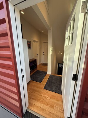 A hallway with a wooden floor, a white door, and a small rug. - Kirkland - Rose Hill Duplex Top Floor Luxurious Oasis + EV (Kirkland)