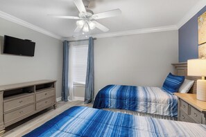 A bedroom with two beds, a ceiling fan, a flat-screen TV, a dresser, and a lamp. - Charming 6 Bedroom House in Kissimmee, 6686 (Orlando)