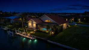 A residential property with a swimming pool, a dock, and a well-lit house at dusk. - Cozy Family House in Punta Gorda, 5919 (Charlotte County)