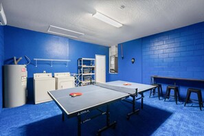 Ein Zimmer mit einem Pongtisch, Wäscheausstattung und einer blauen Ziegelwand.