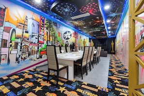 A restaurant with a vibrant mural, a ceiling with star projections, and a carpet with Hollywood-themed designs. - Serene 20 Bedroom Oasis in Davenport City 6690 (Orlando)