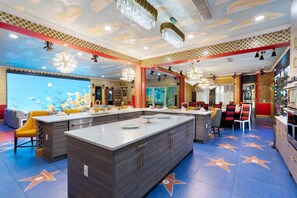 Ein modernes Restaurant mit einer zentralen Kochinsel, einem fußbodenhohen Sternenmuster und einer Decke mit dekorativen Elementen.