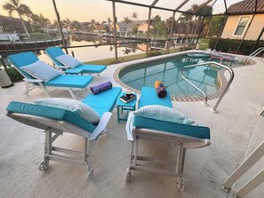 A poolside area with lounge chairs and a small table, overlooking a body of water and a residential area. - Charming Home in Punta Gorda with Spacious Layout, 5925 (Charlotte County)