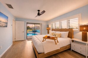 A bedroom with a bed, bedside table, lamp, and a view of a swimming pool. - Modern 3BR House in Punta Gorda, 5923 (Charlotte County)