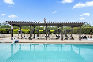 A poolside area with a covered seating area, lounge chairs, and a chessboard. - Modern 4 Bedroom Townhome in Downtown Orlando, 6687 (Orlando)