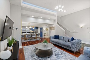 A modern living room with a grey sofa, a round coffee table, and a flat-screen TV. - Modern 4 Bedroom Townhome in Downtown Orlando, 6687 (Orlando)
