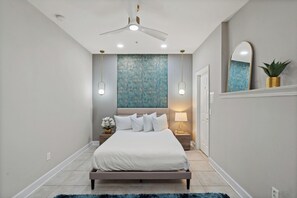 A bedroom with a bed, bedside lamps, a ceiling fan, and a wall with a textured pattern. - Modern 4 Bedroom Townhome in Downtown Orlando, 6687 (Orlando)