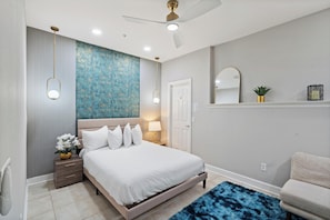 A modern bedroom with a bed, bedside table, lamp, and a blue rug. - Modern 4 Bedroom Townhome in Downtown Orlando, 6687 (Orlando)