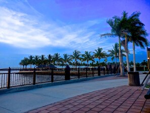 A waterfront promenade with a brick walkway, palm trees, and a metal railing. - Cozy 3 Bedroom House in Punta Gorda, 5921 (Charlotte County)