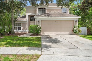 A two-story house with a garage, a driveway, and a well-maintained lawn. - Cozy Home in Davenport for Your Family, 6700 (Orlando)
