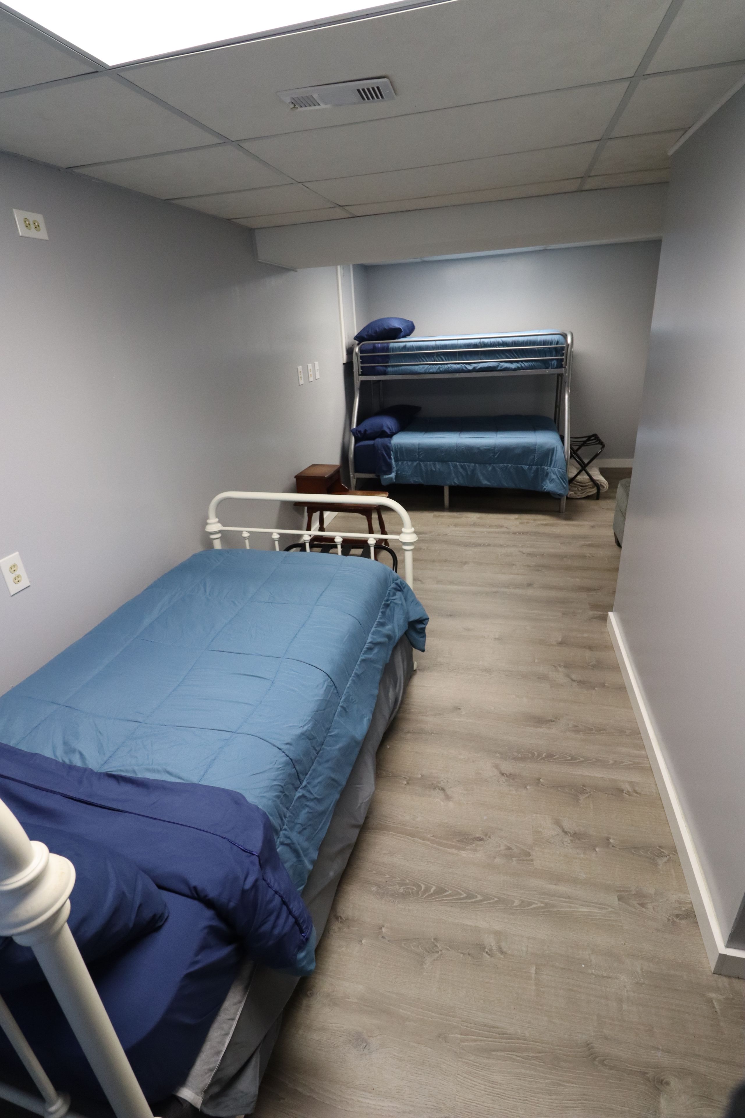 Un dormitorio con dos literas, una cama individual y suelo de madera.