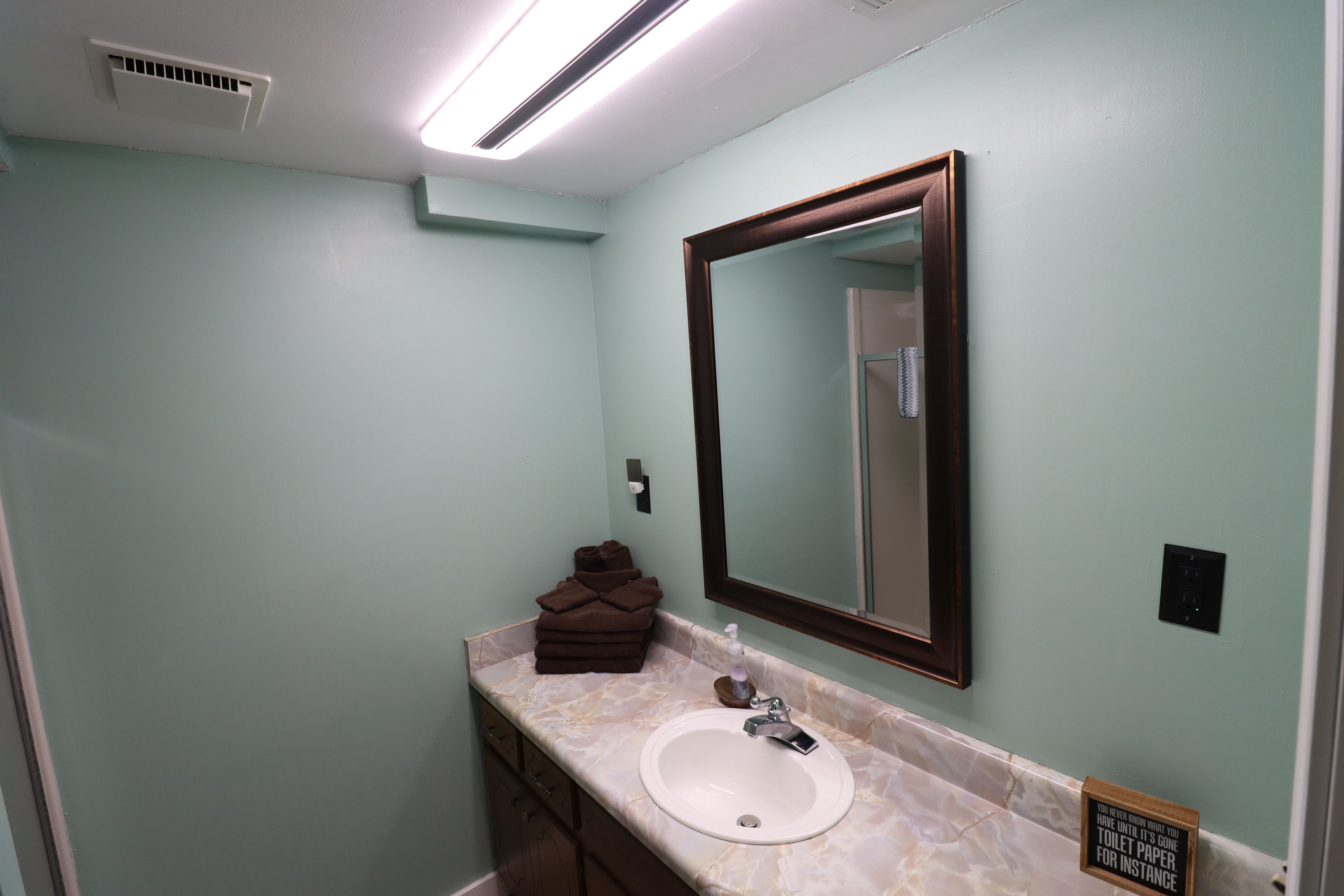 A bathroom with a white sink, a mirror, and a towel rack.
