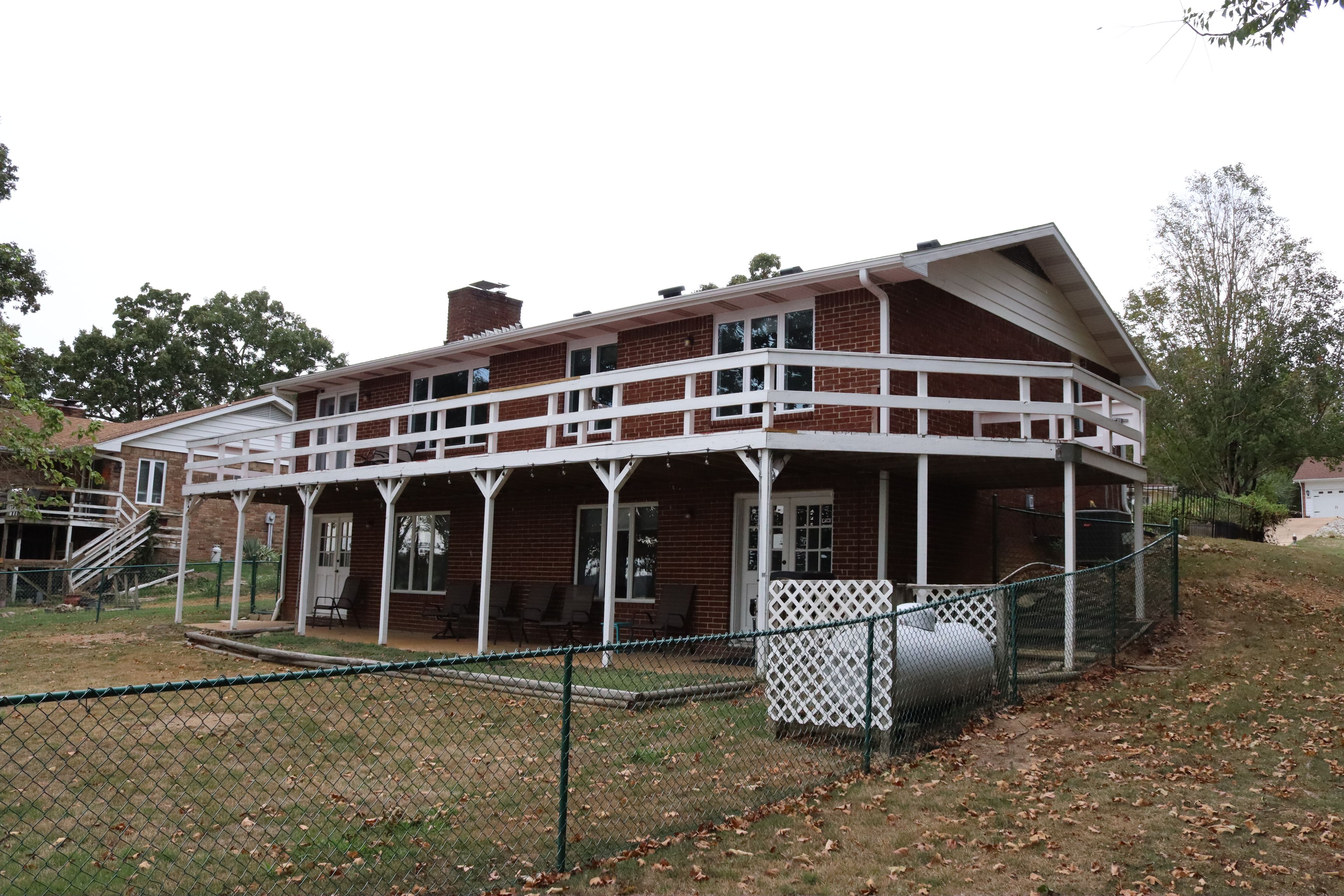 Une maison à deux étages avec un porche et une cour clôturée.