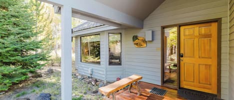 A wooden deck with a bench, a door, and a welcome sign.