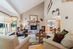 A spacious living room with a stone fireplace, comfortable seating, and a dining area. - Sunriver Fun - Fireplaces, Hot tub & SHARC (Sunriver)