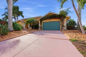 A residential house with a garage, surrounded by palm trees and a well-maintained garden. - Cozy 3 Bedroom Home in Punta Gorda, 5941 (Charlotte County)