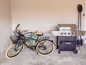 Ein Fahrrad steht neben einem Grill. Im Hintergrund ist eine Mauer zu sehen.