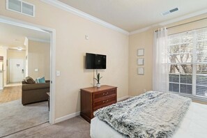 A bedroom with a bed, a dresser, a television, and a window with blinds. - Serene Retreat: 2 Bed Condo in Davenport, 6707 (Orlando)