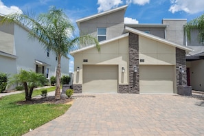 A modern two-story house with a garage, numbered 977 and 979, surrounded by a well-maintained lawn and palm trees. - Serene Urban Oasis in Davenport City, 6706 (Orlando)