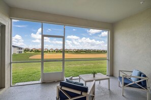 Ein Balkon mit Blick auf ein Baseballfeld, eine Sitzecke mit Tisch und ein Blumentopf.