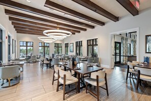 A spacious dining area with multiple tables and chairs, large windows, and a modern ceiling design. - Luxurious 9 Bedroom Mansion in Kissimmee, 6704 (Orlando)