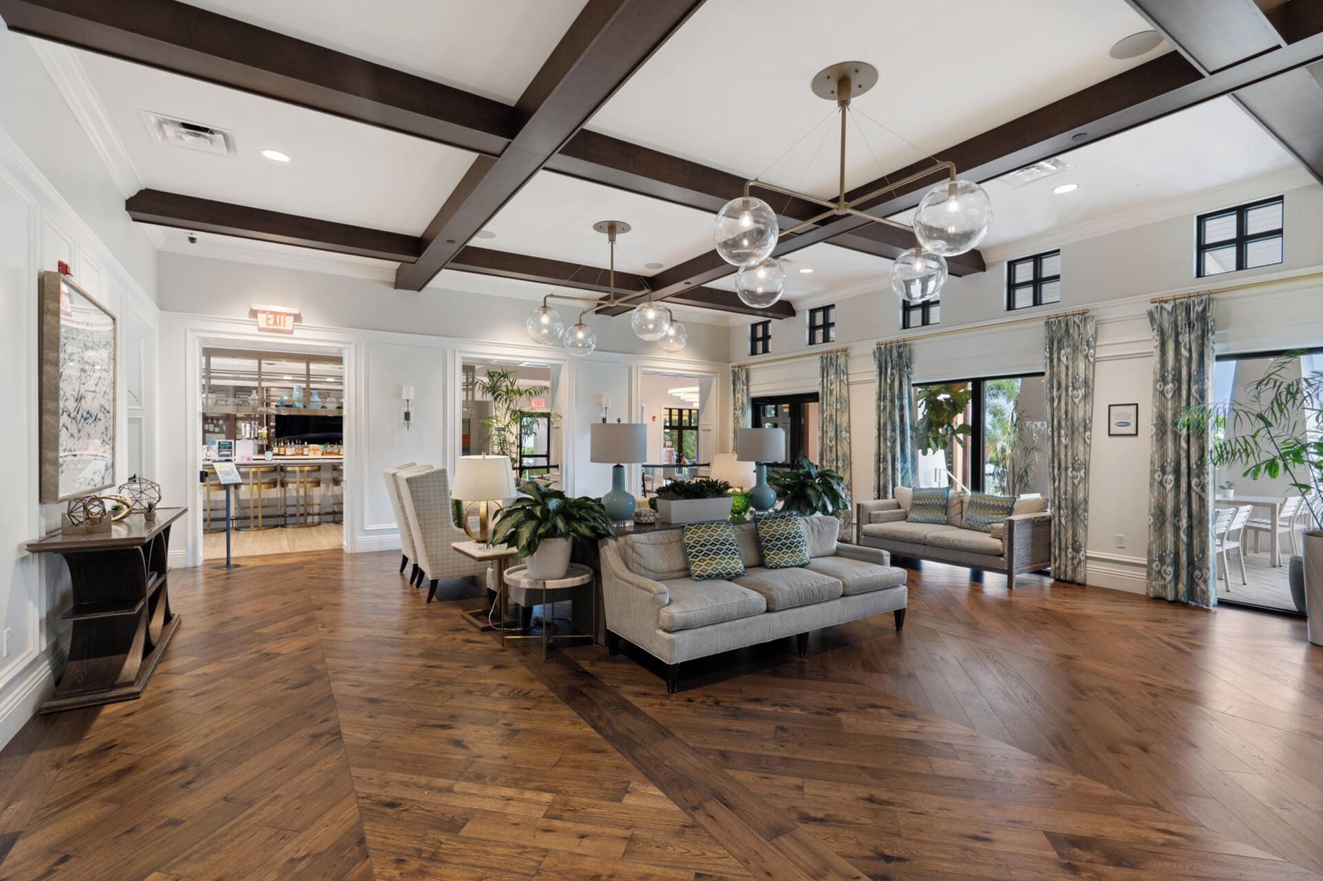 A spacious living area with wooden flooring, a sofa set, and a dining area visible in the background.