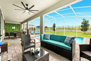 An outdoor patio with a pool, seating area, and a ceiling fan. - Stunning 10 Bedroom Home in Davenport, 6705 (Orlando)