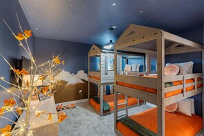 Ein Zimmer mit Etagenbetten, einem geschmückten Baum mit Lichtern und einer Sternenhimmel-Decke.