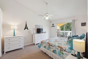 A bedroom with a bed, a dresser, a television, a ceiling fan, and a balcony with outdoor furniture. - Inviting 3 BR Condo in Kissimmee City, 6703 (Orlando)