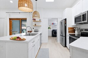 A modern kitchen with white cabinetry, stainless steel appliances, and a central island with fruit. - Inviting 3 Bedroom Home in Punta Gorda, 5947 (Charlotte County)