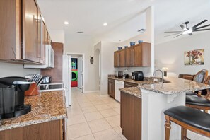 A modern kitchen with granite countertops, wooden cabinets, and a built-in dishwasher. - Spacious Family Home in Kissimmee, 6691 (Orlando)