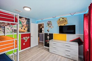 Une chambre d’enfant avec des lits superposés, une télévision et diverses décorations murales.