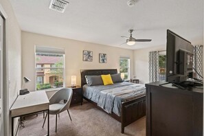 A hotel room with a bed, desk, chair, TV, and a ceiling fan. - Elegant 4 Bedroom Townhome in Davenport, 6694 (Orlando)