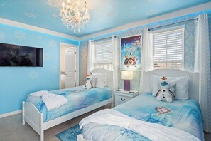A bedroom with two beds, a chandelier, a poster, and a television. - Elegant 10 Bedroom Home in Davenport, 6693 (Orlando)