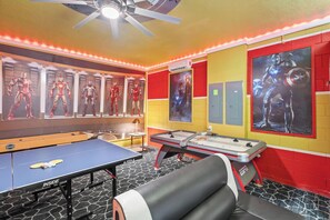 A room with a ping pong table, foosball table, and posters of Iron Man and Captain America. - Elegant 10 Bedroom Home in Davenport, 6693 (Orlando)