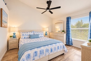 A bedroom with a bed, bedside tables, a ceiling fan, a dresser, a mirror, and a window with curtains. - Cozy Condo with Balcony in Punta Gorda, 6339 (Florida)